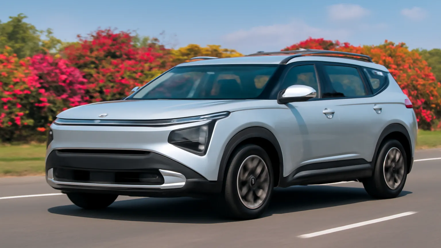 Kia Carens Clavis EV in silver driving on an open highway, showcasing its futuristic design and LED lighting signature.